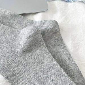 Détail de chaussettes en maille côtelée grise avec texture verticale sur fond en tissu blanc