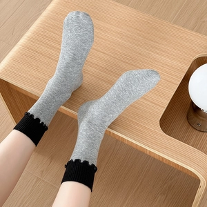 Détail de chaussettes en coton gris avec volants noirs sur un banc en bois