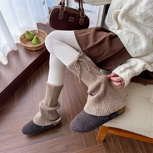 Detail of oat-colored knitted leg warmers with vertical stripes and adjustable ties