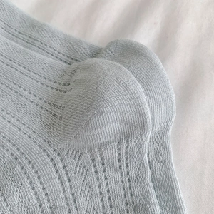 Detailed macro view of light blue mesh socks featuring breathable vertical striped texture