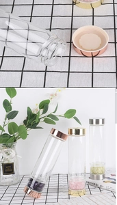 Detalle de botella de cristal con piedras de energía natural y tapa de metal rosado