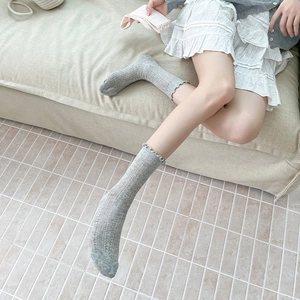 Detailed view of light gray openwork knit crew socks with ruffled cuffs for women