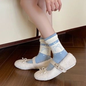 Detail of white Mary Jane shoes paired with blue bow-knot patterned knit socks