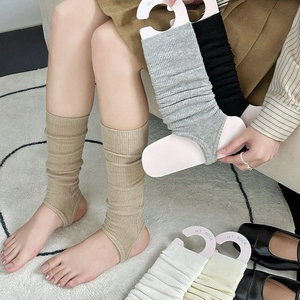 Detailed knit texture of grey stirrup leg warmers paired with black leather shoes