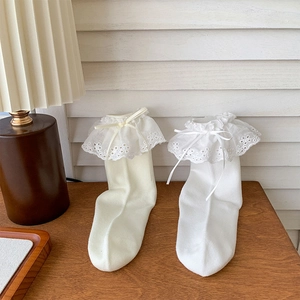 Detail of white ballet-style socks featuring delicate lace embroidery and ribbon bows