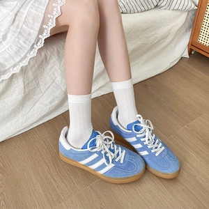 Vue détaillée de baskets rétro en daim bleu avec rayures blanches et semelle en gomme