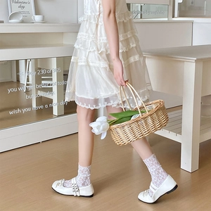 Détail de chaussures Mary Jane blanches avec nœuds et chaussettes en dentelle douce