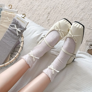 Detail of cream Mary Jane shoes with bow decoration and white lace mesh socks