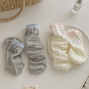 Détail de chaussettes ours mignonnes avec nœuds et boutons en rose pastel et crème
