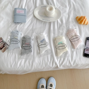 Detail of five pairs of pastel mesh socks with bows on a cozy lifestyle background