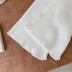 Detail of white ribbed knit fabric with soft texture on a wooden table setting