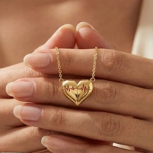 Close-up of 18K gold-plated heart pendant with red heartbeat detail on a delicate chain