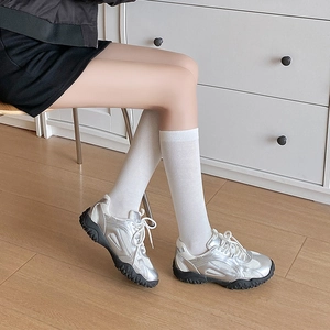Silver athletic sneakers paired with white mid-calf socks for a casual college look
