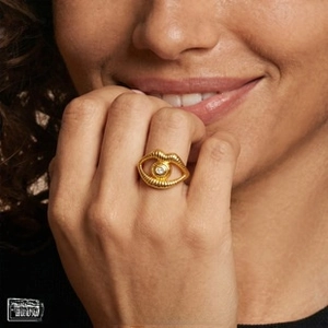 Close-up of surrealist 18K gold-plated ring with eye and lip motif and central gemstone