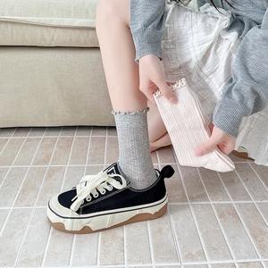 Detail of ribbed knit crew socks with ruffle edges styled with black platform sneakers
