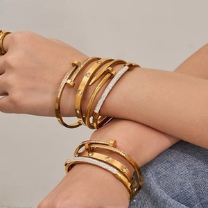 Close-up of stacked 18K gold plated PVD titanium steel bangles with crystal details