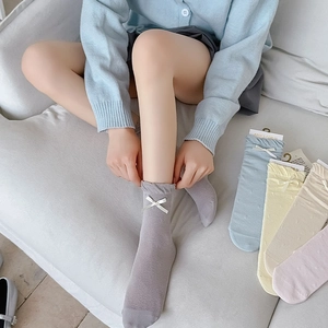 Close-up of ballet style mesh socks with ribbon bows and ruffled edges in soft pastel colors