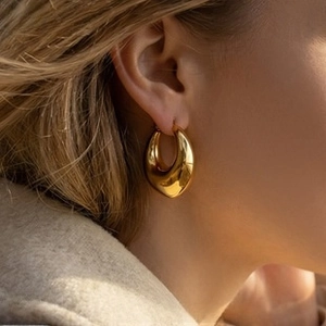 Close-up of elegant gold-plated drop earrings worn by a model in a luxury setting