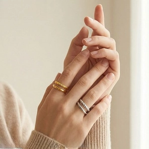 Detailed view of layered 18K gold and silver plated twist rings on model's hand