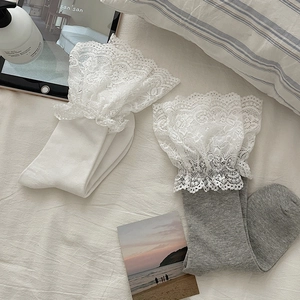 Close-up of elegant white and grey knit socks featuring oversized delicate floral lace cuffs