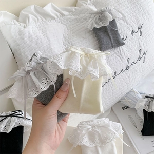 Detail of white ballet-style socks featuring lace trim and a delicate ribbon bow