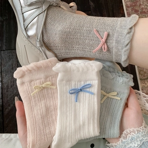 Close-up of knit hollow mesh socks with ruffled lace edges and cute ribbon bows