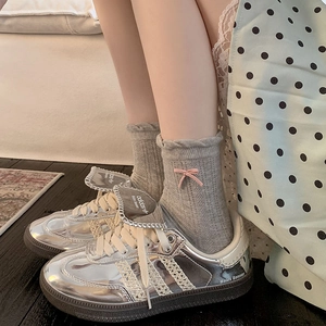 Macro shot of silver metallic sneakers with lace stripes and ruffled socks with pink bows