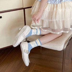 Close-up of blue and white socks with bow patterns paired with fuzzy Mary Jane shoes