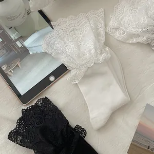 Detail of sweet Lolita knee-high socks with elegant lace ruffle cuffs in white and black