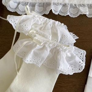 Detail of white rib-knit socks with elaborate lace ruffles and delicate satin bows