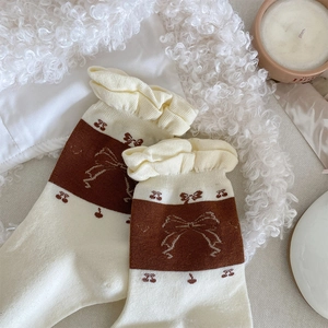 Close-up of vintage beige mid-calf socks with ruffle trim and cute cherry bow patterns