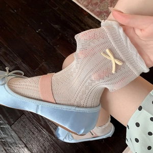 White lace mesh socks with yellow bow detail worn with ballet flats on dark wood background