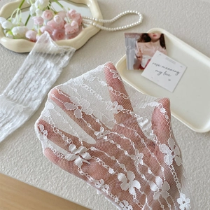 Close-up of white lace socks with floral embroidery and breathable mesh texture