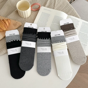 Gros plan de cinq paires de chaussettes en coton côtelé à bords volantés aux tons neutres