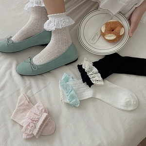 Dettaglio di calze dolci con volant in pizzo in colori pastello e trama a maglia