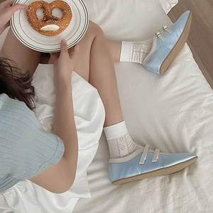 Detail of light blue satin ballet flats with white heart cutout socks in a cozy setting
