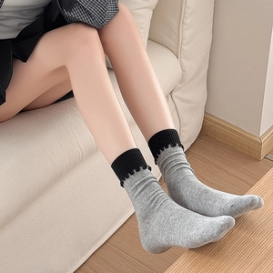 Détail de chaussettes en maille grise avec bords noirs ondulés dans un décor intérieur