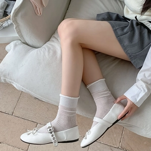 Dettaglio di scarpe Mary Jane bianche con fiocco e calze a rete abbinate