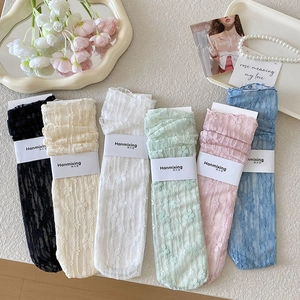 Detail of floral lace mesh socks in pastel colors with daisy patterns and branding