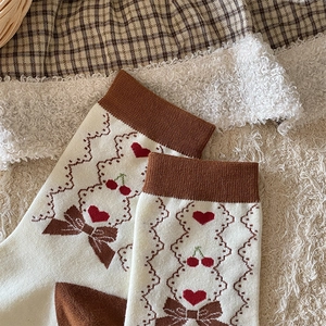 Detail of sweet knit socks with cherry and bow patterns on warm fuzzy background