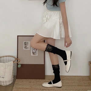 Elegant white Lolita style knee high socks with black lace trim and Mary Jane shoes