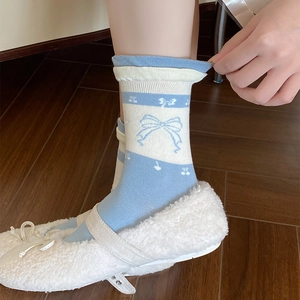 Close-up of sky blue and white mid-tube socks with cherry patterns and sweet bow accents