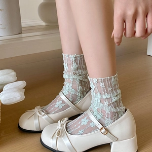 Detail of light blue floral lace socks paired with beige Mary Jane shoes and silk bows