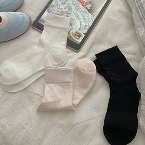 Close-up of three mid-calf socks in white, pink, and black with hollow dot knit patterns