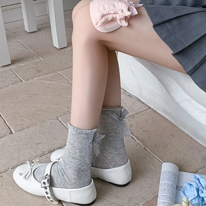 Detail of grey mesh socks with knit bow accent and hollow mesh texture worn with Mary Janes