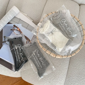 Bow heart pendant socks in a four-pack neutral color set inside a woven basket