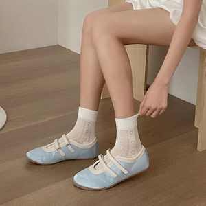 Light blue satin ballet flats paired with off-white heart patterned crew socks on wood floor