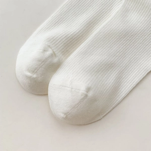 Close-up of white rib-knit cotton blend socks showing fine texture and seamless toe detail
