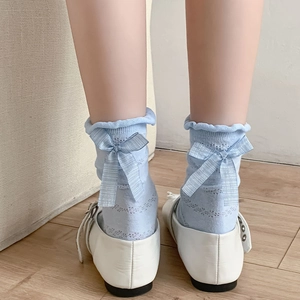 Close-up of light blue hollow knit socks with silk bow detail and wavy lace edges