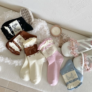 Close-up of vintage cotton crew socks featuring bow patterns and ruffled cuffs in soft tones